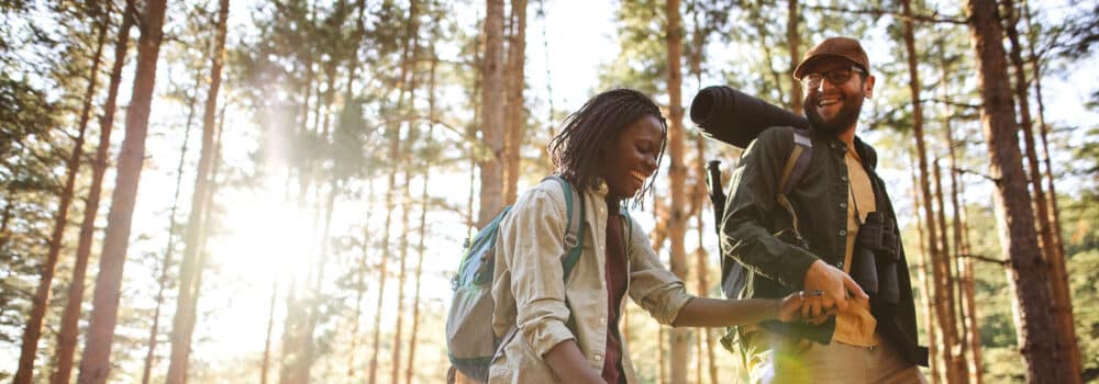 Couple hold hands while hiking in the forest