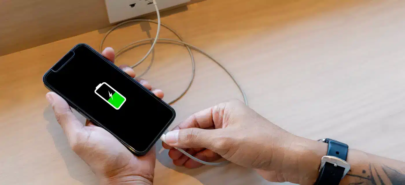 An iPhone showing that the battery life is half full is being plugged into it's charger.
