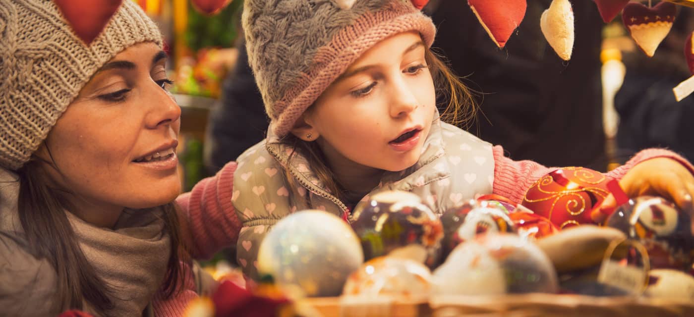 A woman and a young girl looking at Christmas decorations.