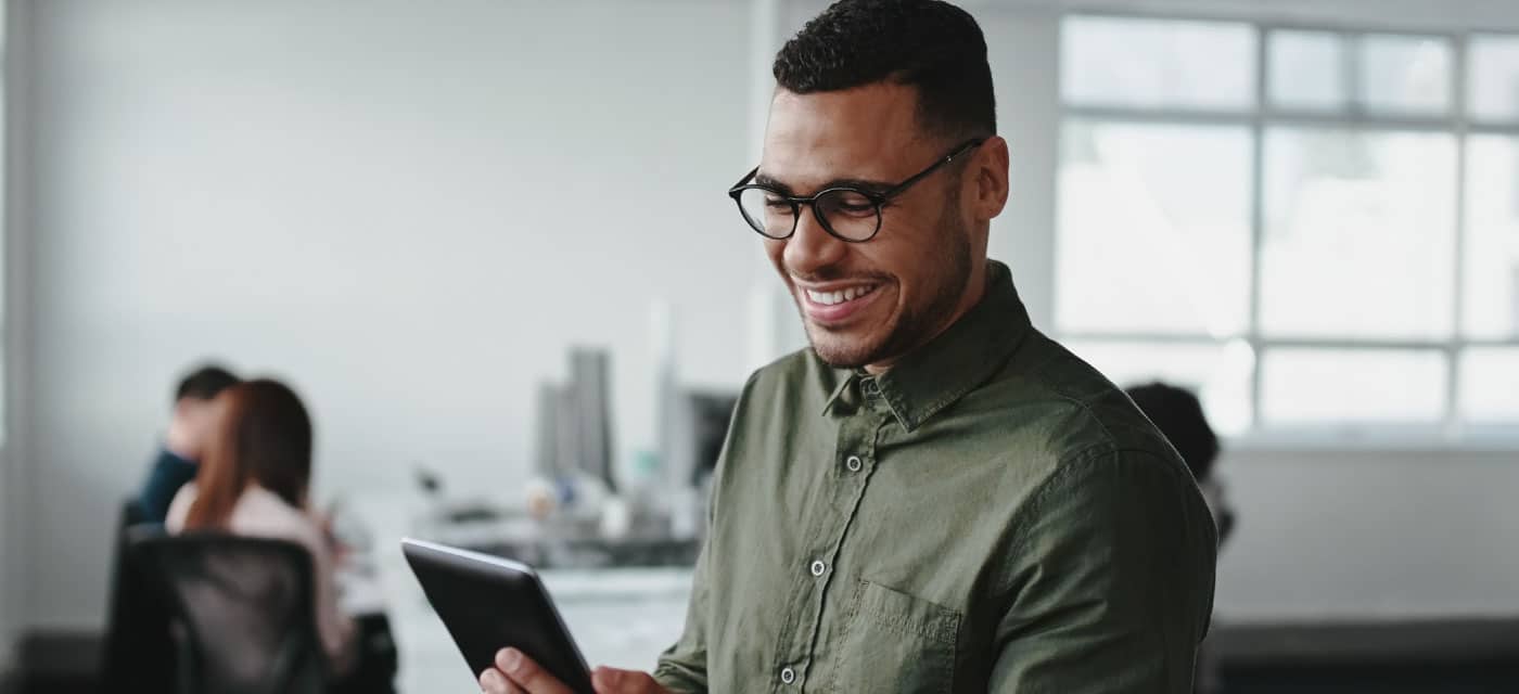 A man smiling and looking at a tablet.