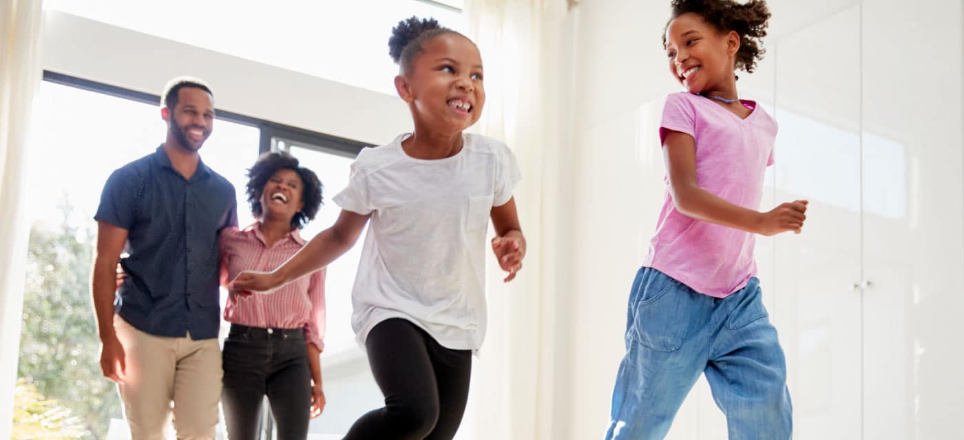 Family walking inside a home, they are smiling and laughing.