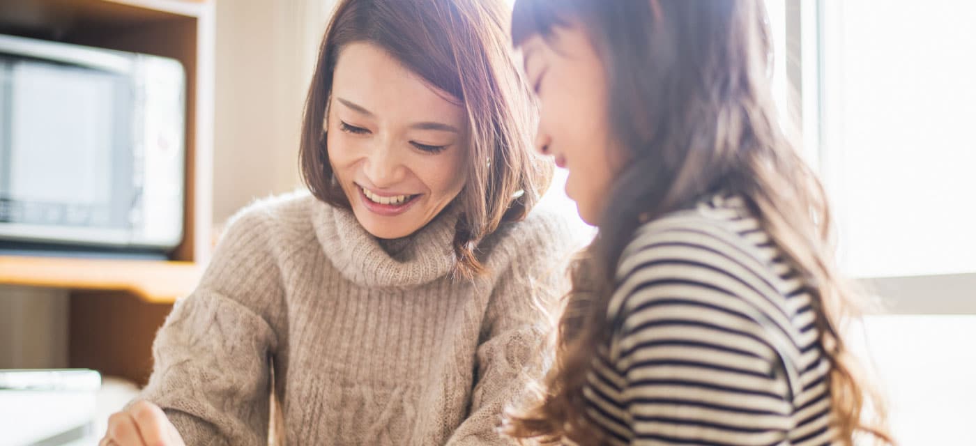 A woman and a young girl writing on a piece of paper and smiling.