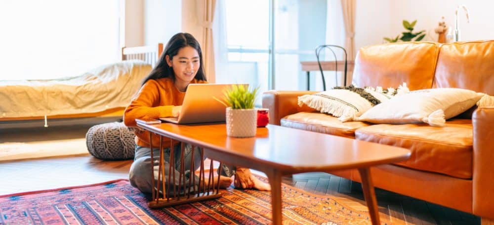 A woman sitting at a coffee table, using a laptop.