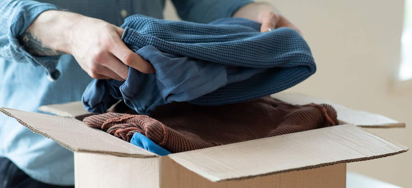 Person packs folded clothes into cardboard box