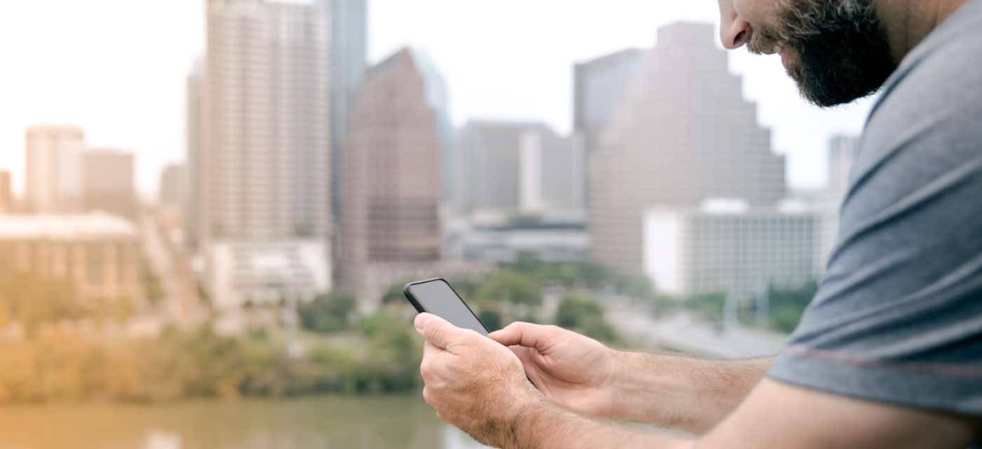 A man using a cell phone and standing outside.