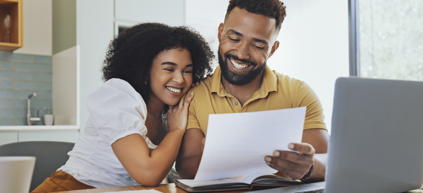 Couple reviewing a document in front of a laptop.