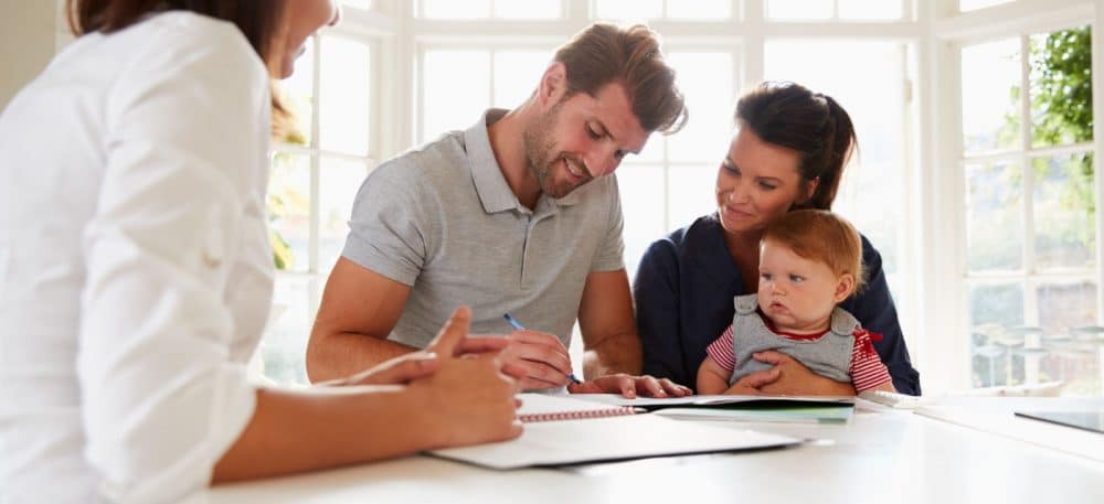 A family signing papers with a realtor present.