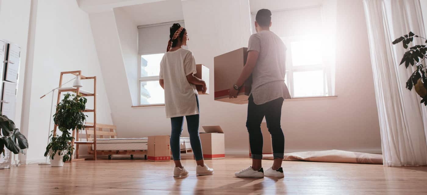 A couple standing in an empty house with moving boxes.
