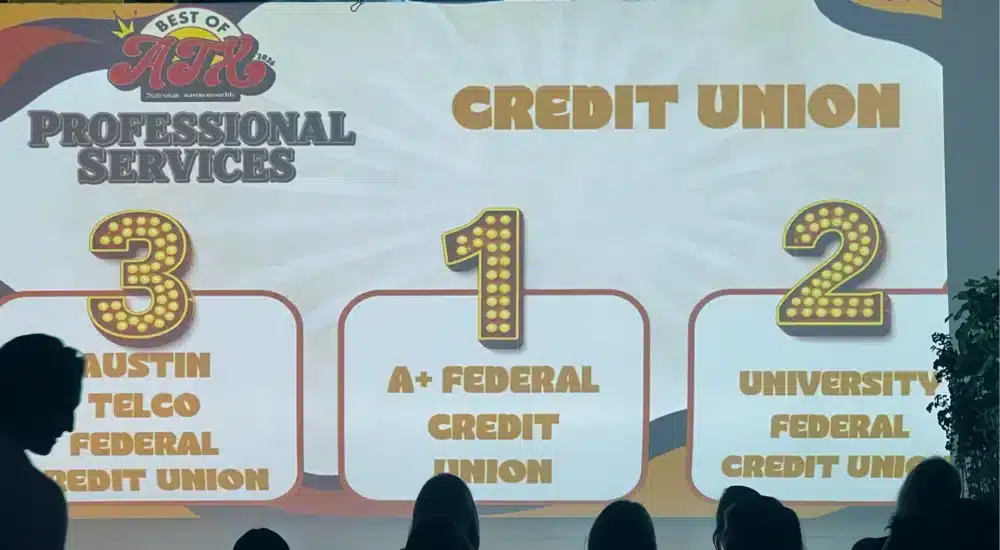 Stage backdrop advertising Credit Union with a 3-1-2 podium and audience silhouettes in front of large gold-lettered numbers.