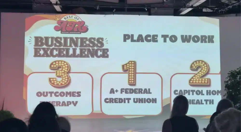Stage banner reads 'Business Excellence' and 'Place to Work' with large numbered podiums 3, 1, 2 and category list partially visible in the foreground.