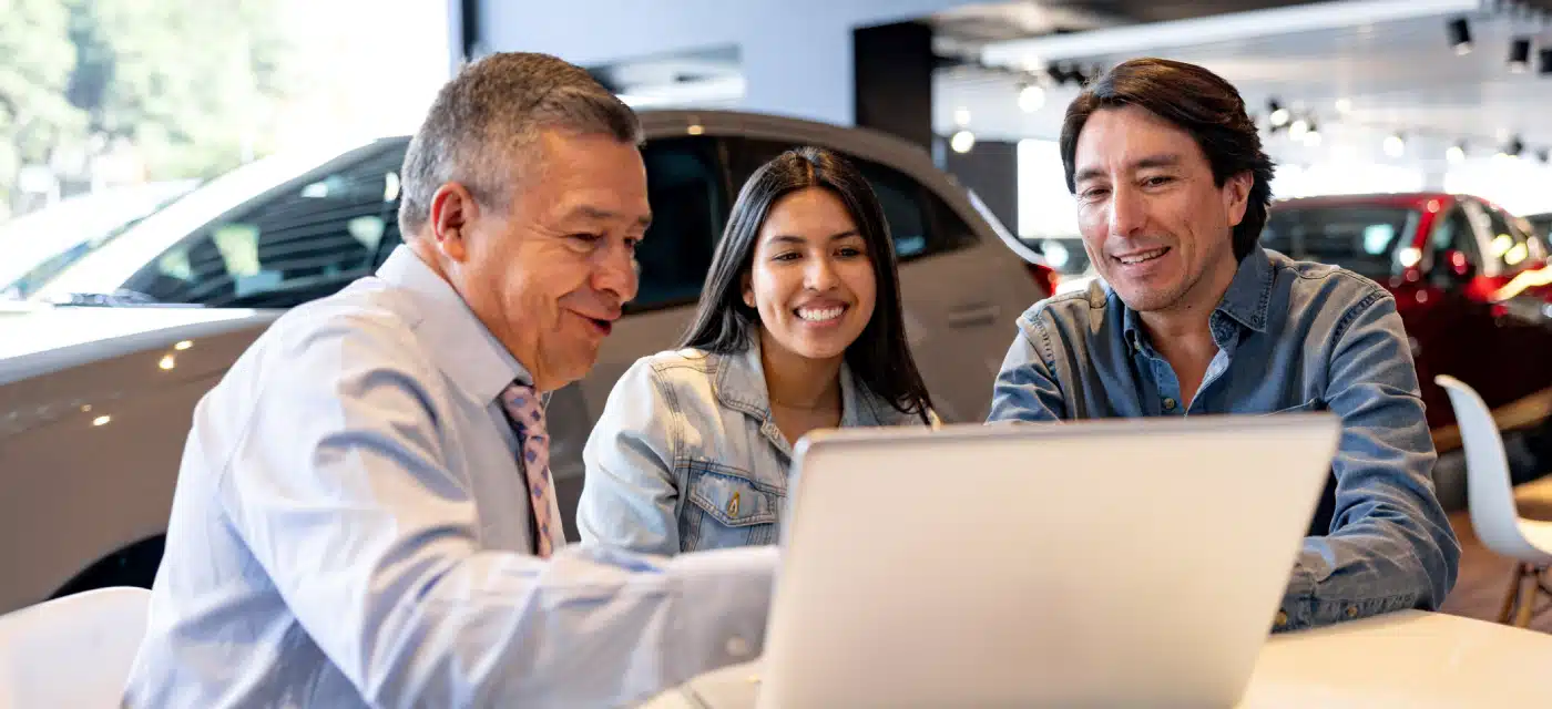 Couple looking at a laptop with a finance manager at a dealership