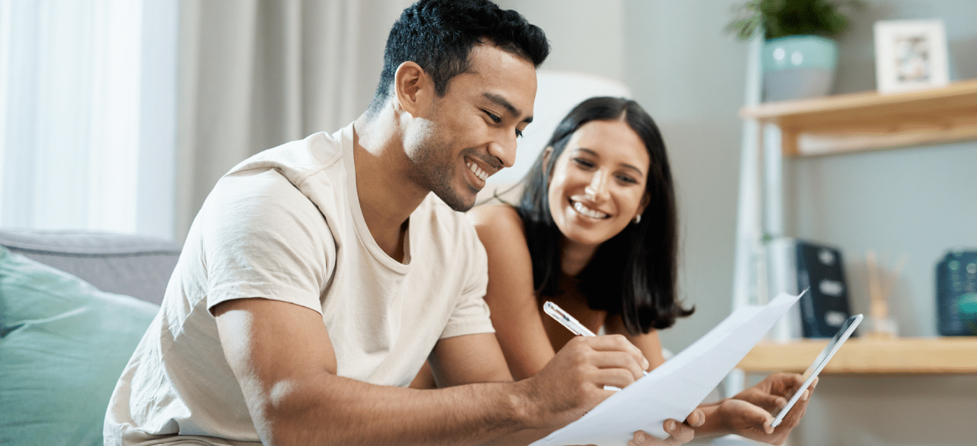 Couple sitting on the couch reviewing a document.