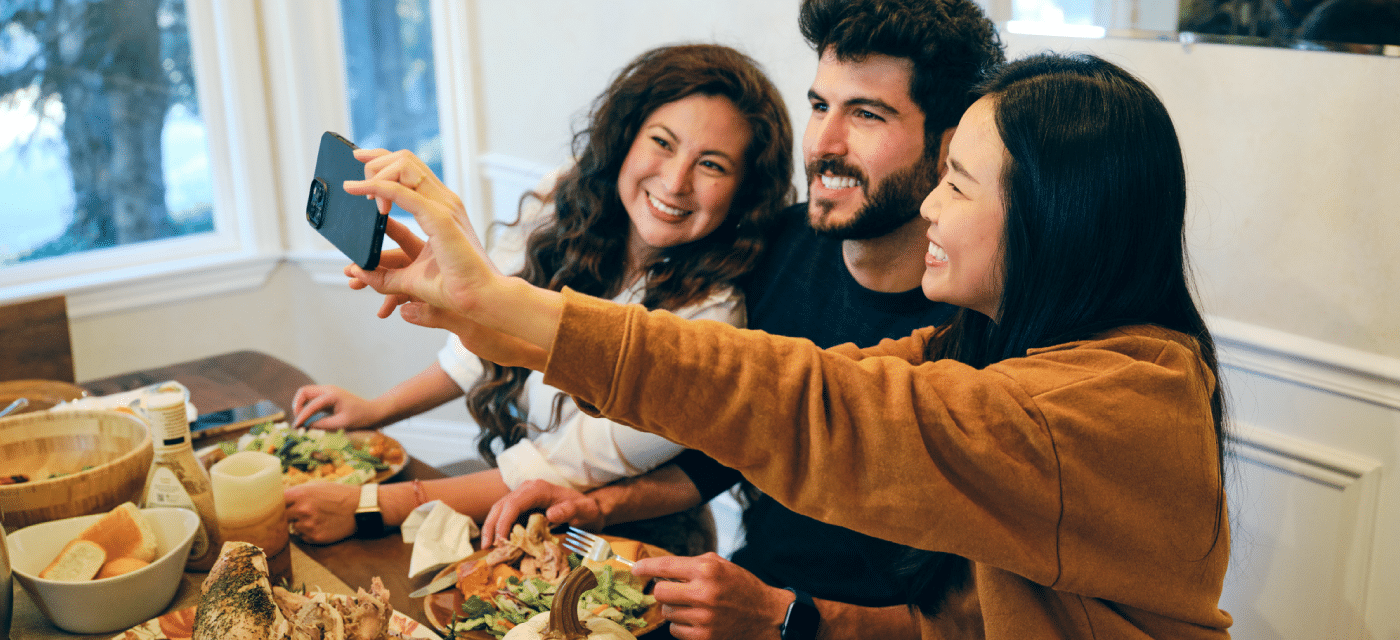 Three friend/family members taking a selfie at the dinner table