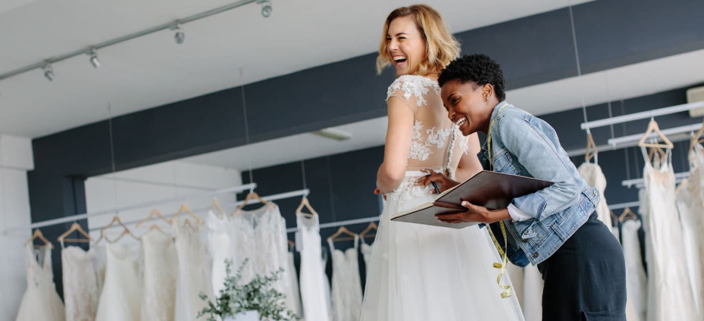 A woman trying on a bridal dress with a sales associate.