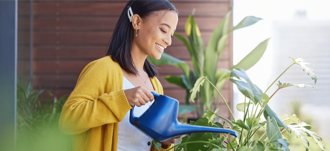 Woman smiling while watering houseplants.