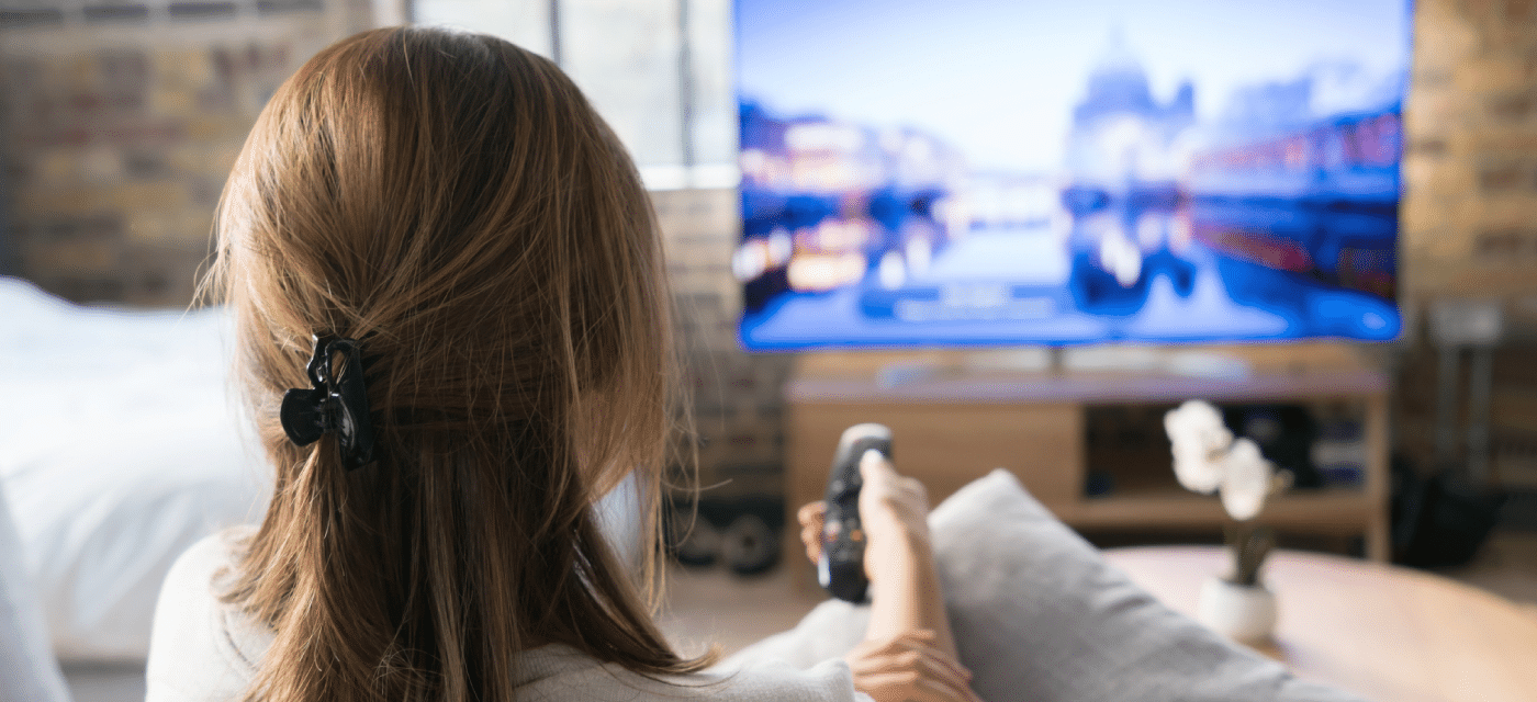 Woman relaxing at home and flipping through television channels.