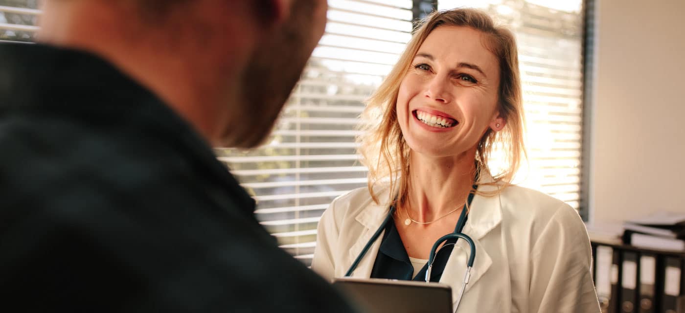 A man talking to a female doctor, the doctor is smiling.