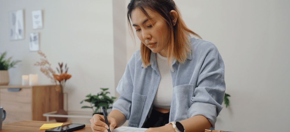 Woman sitting at her table reviewing a document.