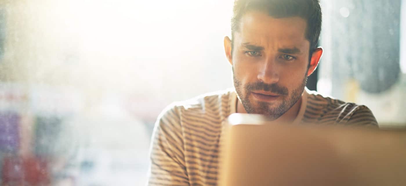 A man looking at something on a laptop, he appears to be worried.