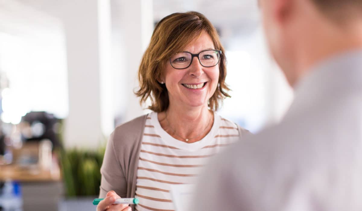 An older woman talking to a man, she is smiling.