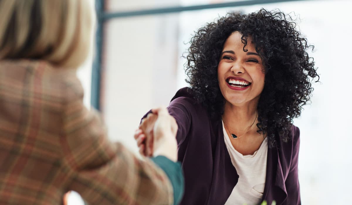 Two women shaking hands and smiling.