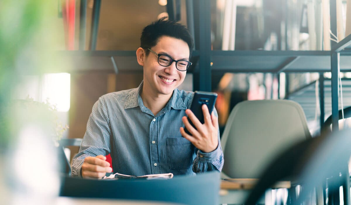 A man smiling and looking at his cell phone.