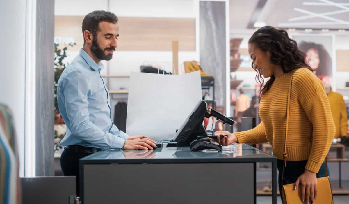 A woman shopping, a man swipes her credit card.