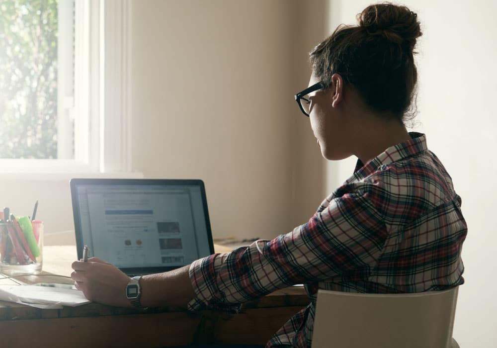 A woman uses a laptop while sitting at a desk.