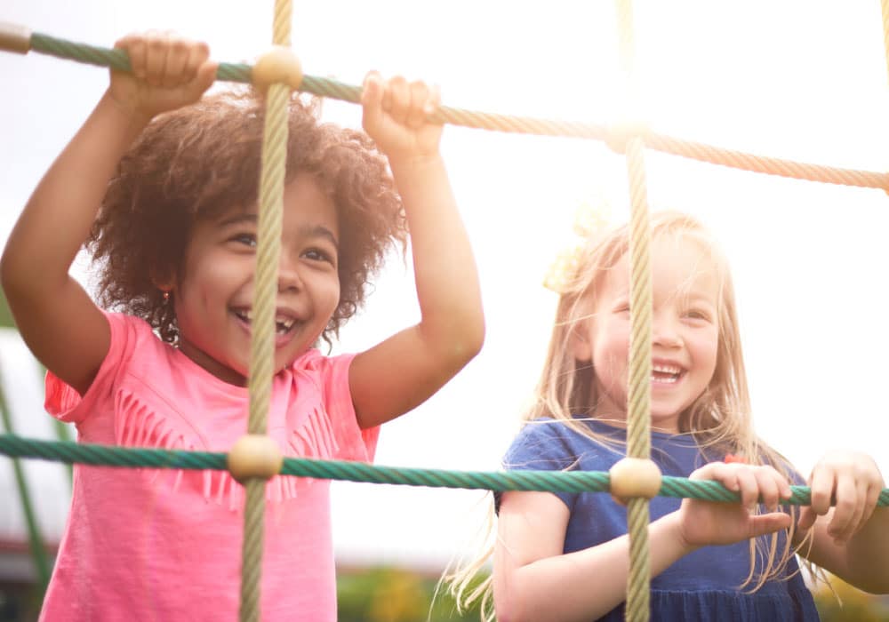 Two young girls playing on a playground.