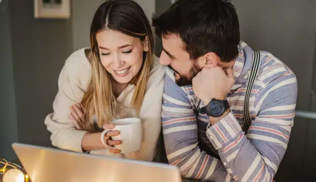 Man looking at women as she looks at a computer.