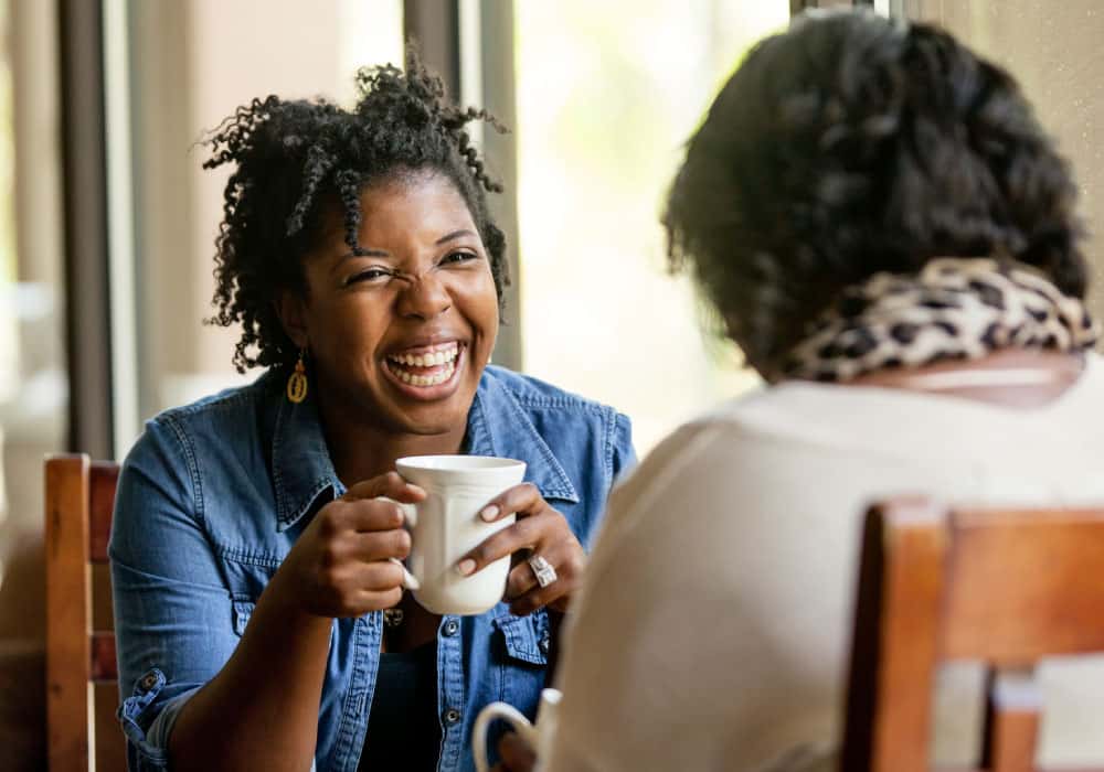 Two women sharing coffee and smiling.