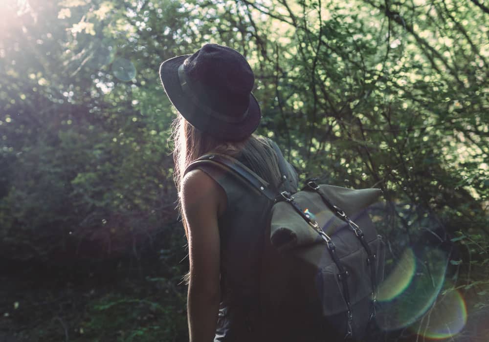 A woman with backpack hikes in wooded area.