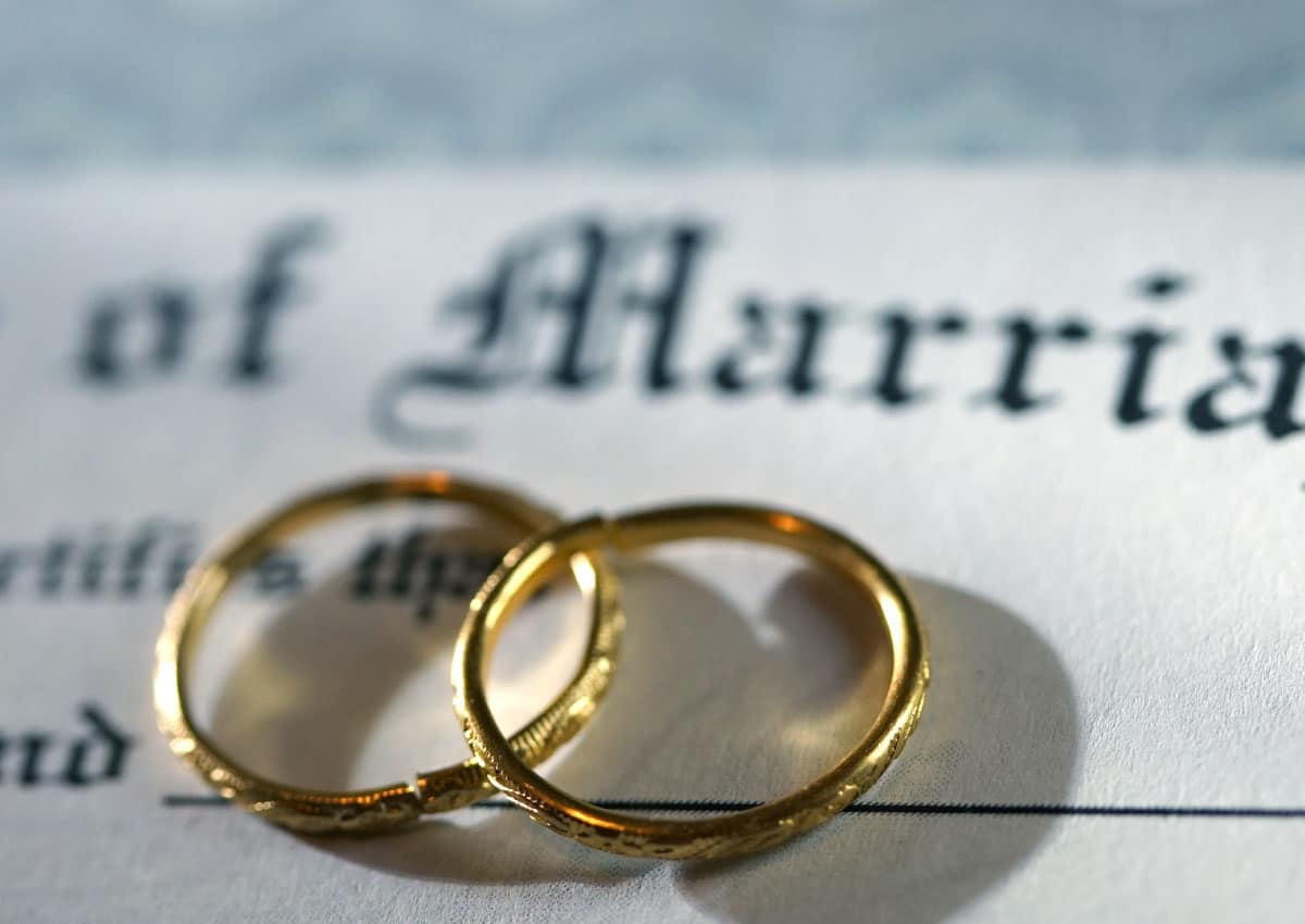 Two gold rings lay on top of a marriage certificate