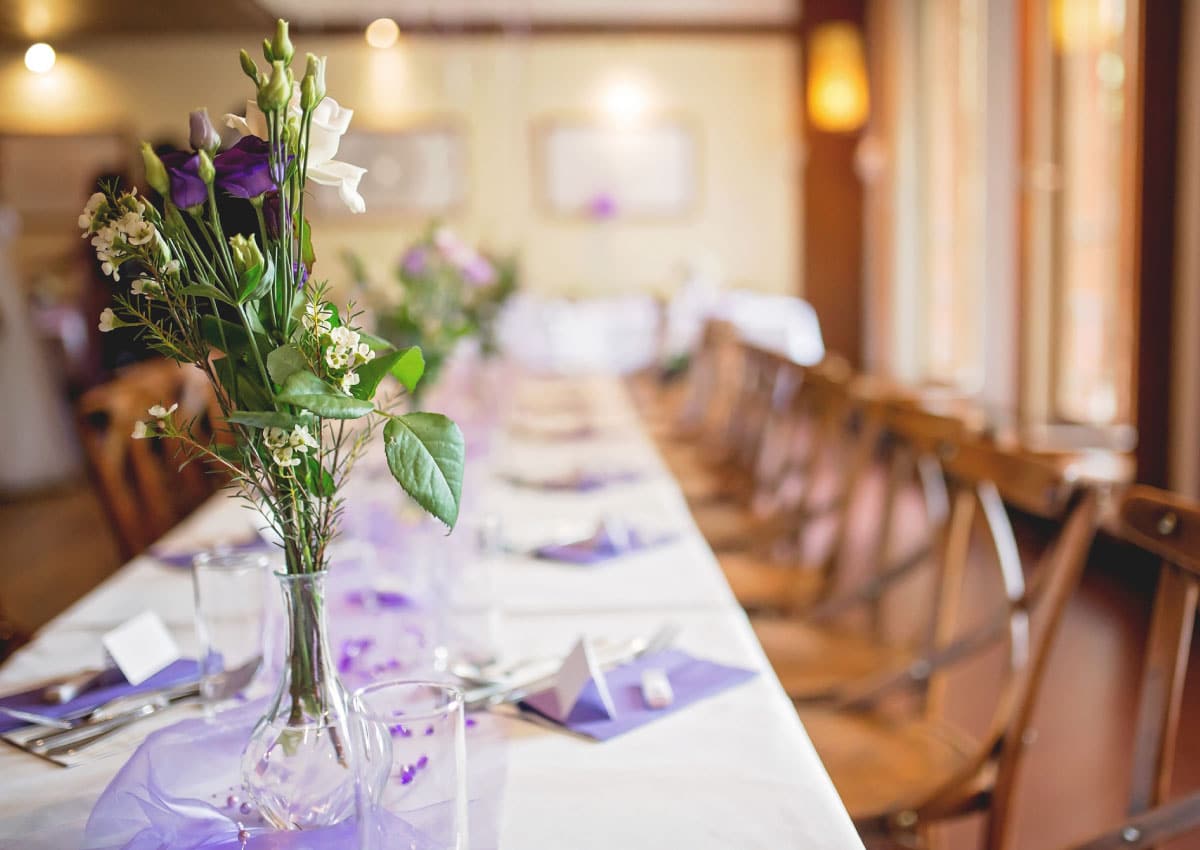 Long banquet table with purple place settings and flowers in vases