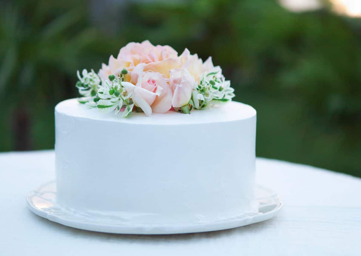 White frosted cake with light pink flower accents on top