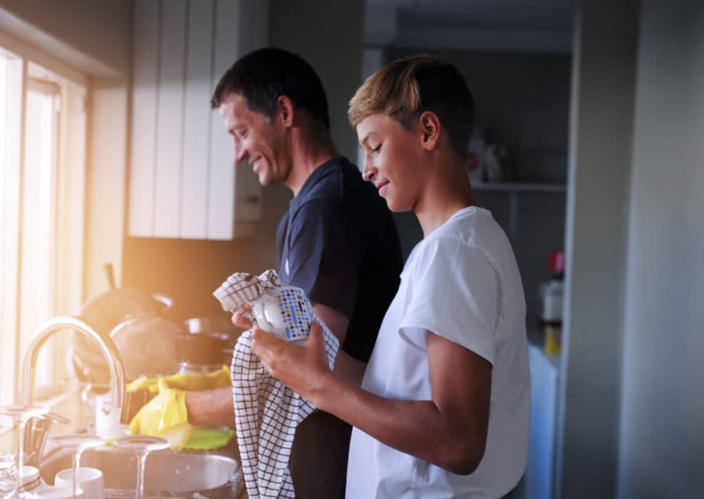 Father and son wash dishes together