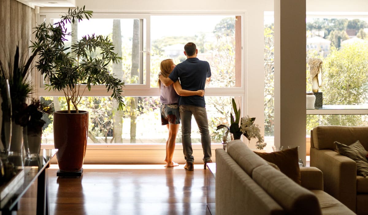 A couple standing in front of the window in a home.
