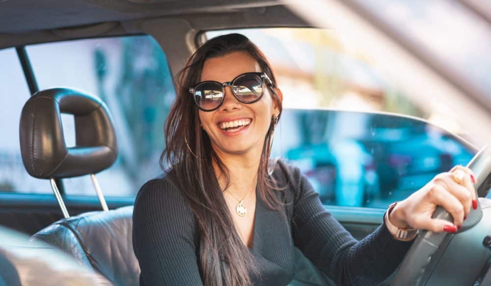 A woman driving a car and smiling.