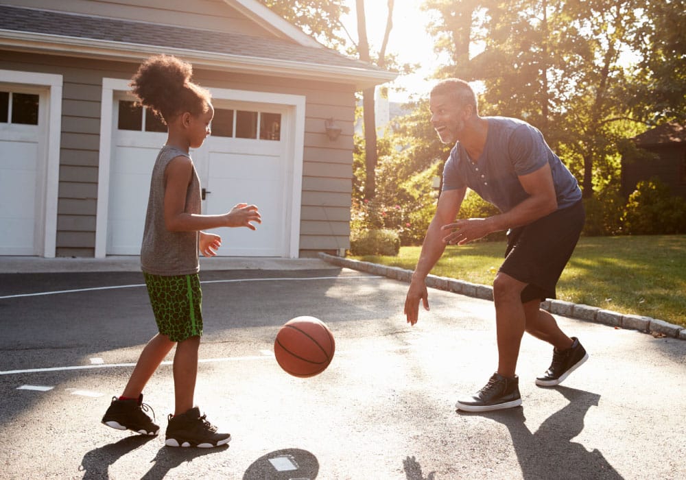 A young girl plays basketball with an older man