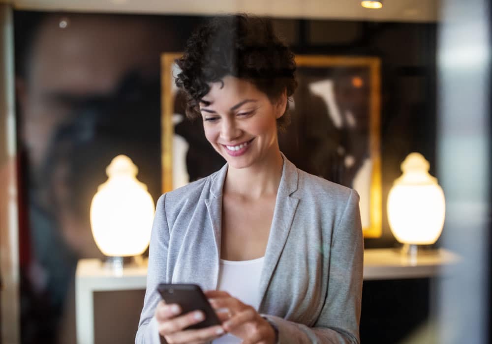 Woman stands in foyer of store looking at mobile phone