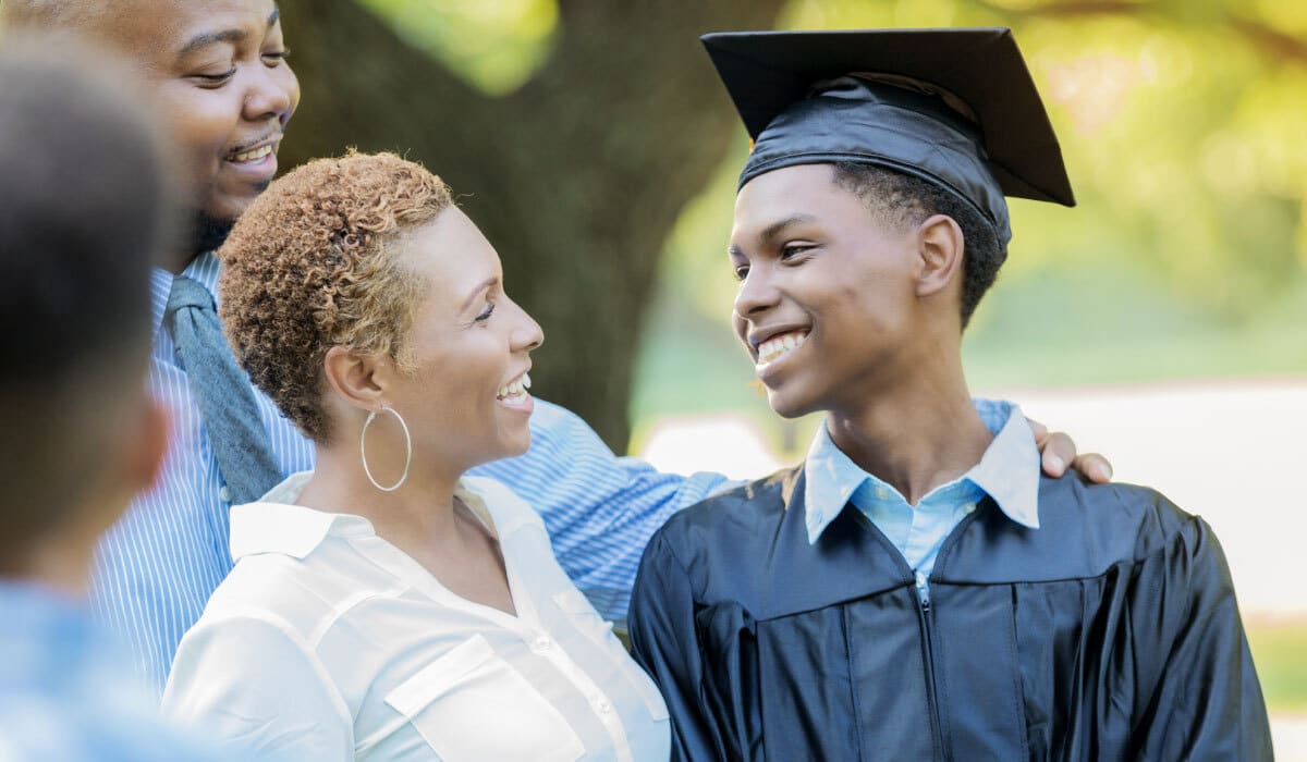 A woman looking at a young boy in a graduation cap and gown and smiling