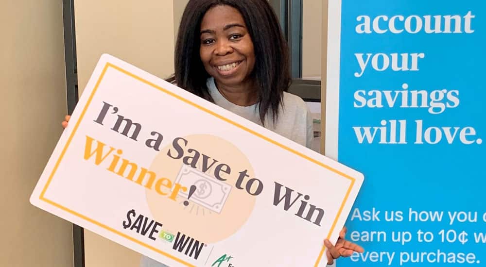 A+FCU member holds I’m a Save to Win Winner sign.