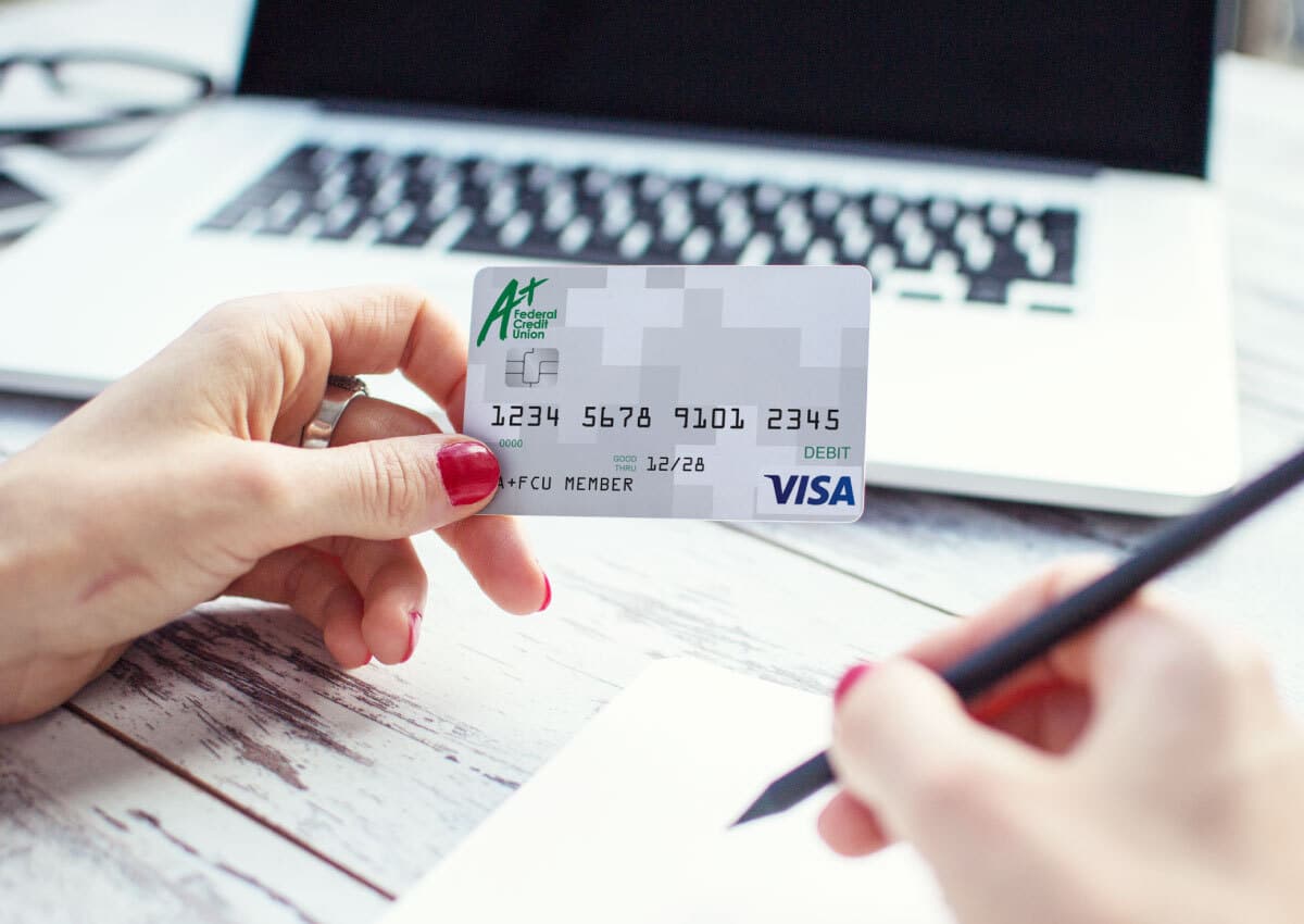 A woman using an A+ Federal Credit Union Visa Debt Card
