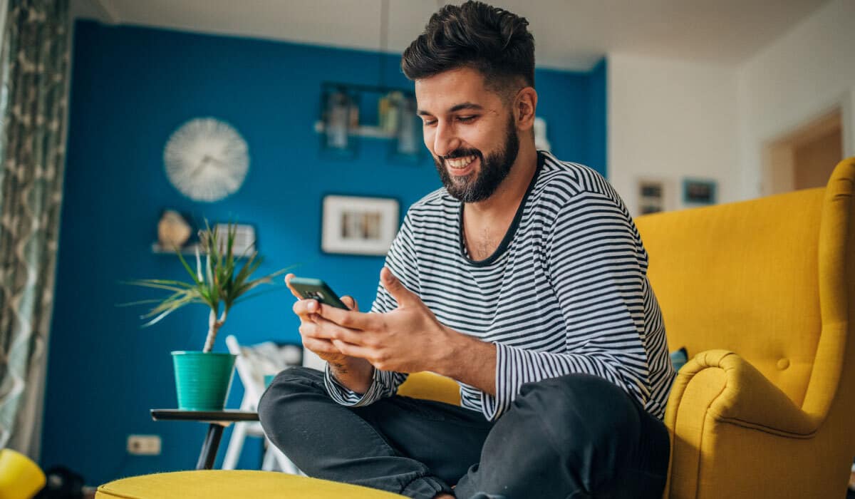 A man using a cell phone while sitting on a comfortable chair.