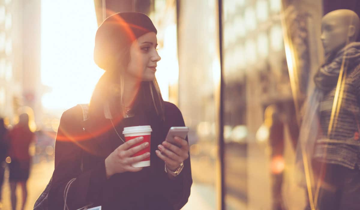 Credit union online banking. A woman walking and holding a cell phone.