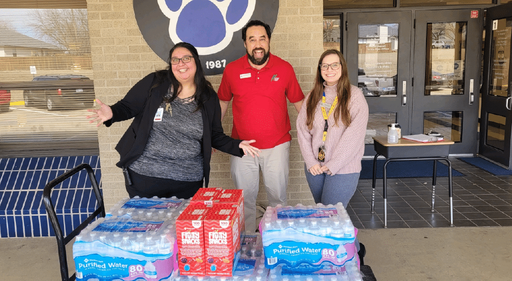 A+FCU employees drop off water and snacks to a school