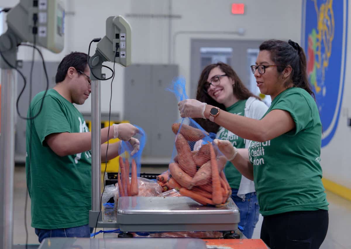 A+FCU volunteers pack bags of sweet potatoes and carrots at the Central Texas Food Bank.