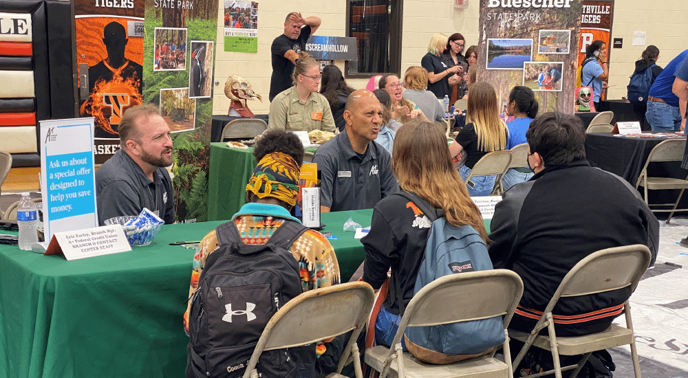 Two A+FCU team members talk with students at a career day