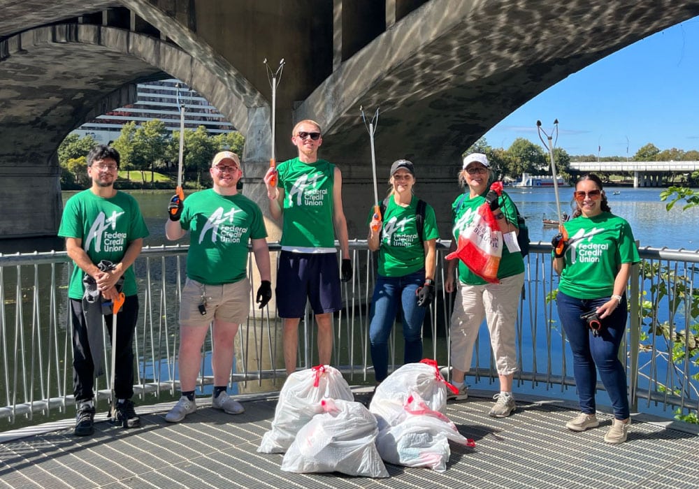Team A+ poses outside Lady Bird Lake after picking up trash on a walking path.