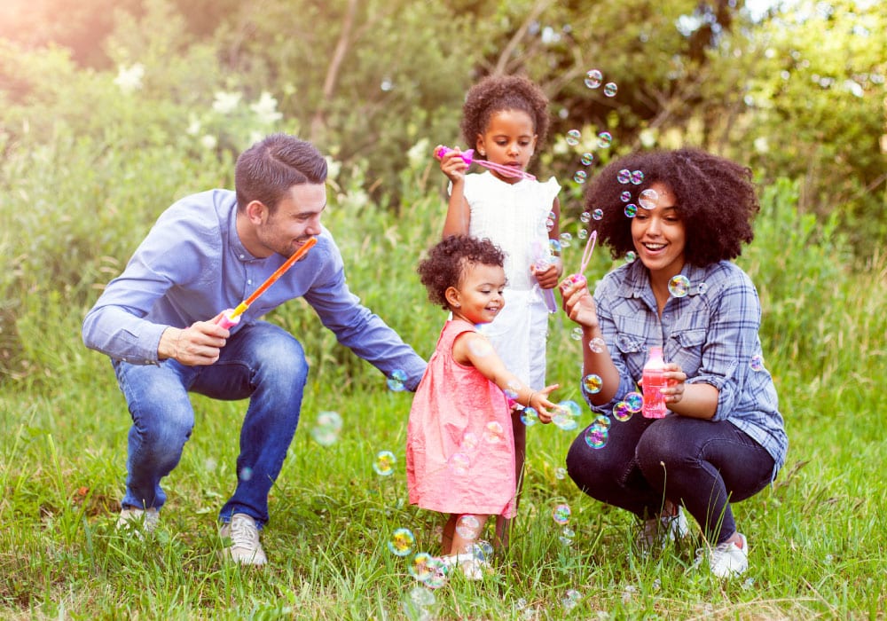 A family plays with bubbles in an outdoor park.